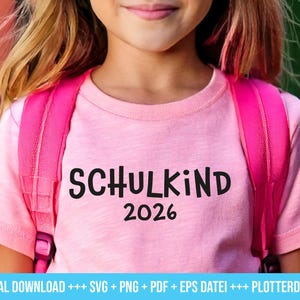 Può includere: Una maglietta rosa con la scritta "SCHULKIND 2026" in nero. La maglietta è indossata da una persona con uno zaino rosa. L'immagine è un download digitale, come indicato dal testo in basso.