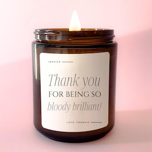 May include: A brown glass candle with a white label that reads "Thank you for being so bloody brilliant!"  Love, Frankie. The candle is lit and the flame is visible.