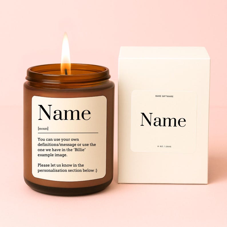 May include: A brown glass candle with a white label that says "Name [noun] You can use your own definitions/message or use the one we have in the 'Billie' example image. Please let us know in the personalisation section below :)" The candle is lit and the box is white with the word "Name" printed on it.