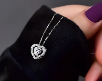 May include: A silver necklace with a heart-shaped pendant featuring a sparkling clear stone surrounded by smaller stones.