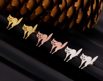 May include: Five pairs of cat-shaped earrings in different colors. The earrings are made of metal and have a shiny finish. The colors are gold, rose gold, silver, and two shades of silver.