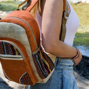 Mittelgroßer, orangefarbener Hanfrucksack mit lebendigem, ethnisch anmutendem Himalaya-Webmuster, handgefertigt in Nepal, Unisex-Boho-Stil, originelles und umweltfreundliches Geschenk