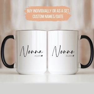 Peut inclure: Deux mugs en céramique blancs avec des anses et des bords noirs. L'un des mugs porte l'inscription "Nonna Again" et l'autre "Nonno Again" en écriture noire. Les mugs sont présentés sur une surface blanche.