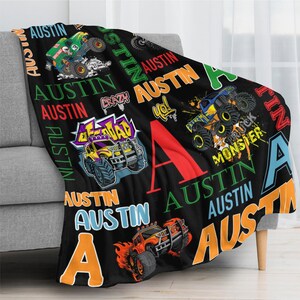 May include: Black fleece blanket with colorful monster truck graphics and the name "Austin" in various fonts. The blanket features a large red "A" and other design elements.