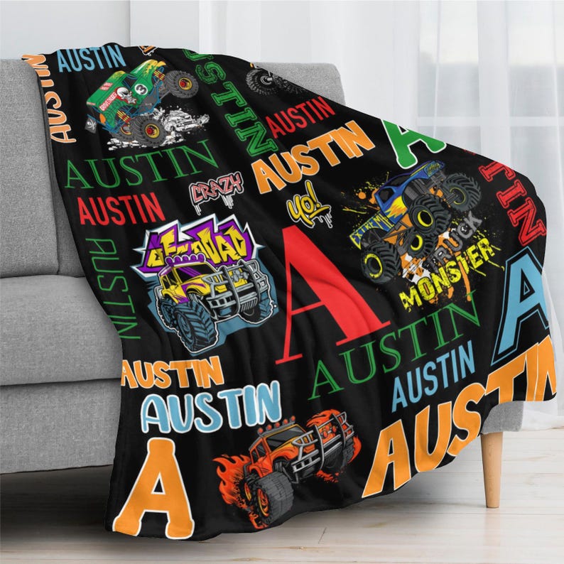 May include: Black fleece blanket with colorful monster truck graphics and the name "Austin" in various fonts. The blanket features a large red "A" and other design elements.
