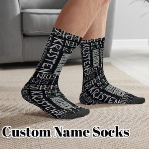 May include: A pair of black custom name socks with the name "Kristen" repeated in white lettering. The socks are shown on a person's feet.