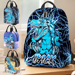 May include: A black backpack and three lunch bags featuring a blue dinosaur design with lightning bolts. The name "JACK" is printed in white on each bag. The backpack has a black handle and zipper.