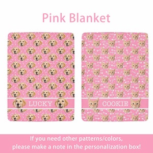 May include: Two pink blankets with pet-themed designs. One features a pattern of golden retriever faces and bone shapes, with the name "LUCKY" on a white stripe. The other blanket has a pattern of cat faces and fish bones, with the name "COOKIE".
