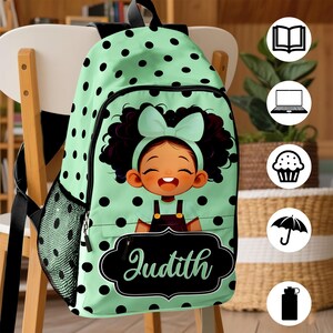 May include: A light green backpack with black polka dots featuring a cartoon illustration of a child with dark curly hair and a light green bow. The front pocket displays a black decorative label with the name Judith written in white script.