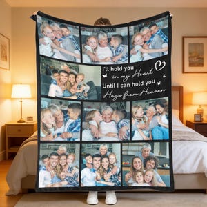 May include: A black blanket featuring a collage of family photos. The blanket has a black border and includes the text "I'll hold you in my Heart Until I can hold you Hugs from Heaven" in white script. The blanket is held up by a person.