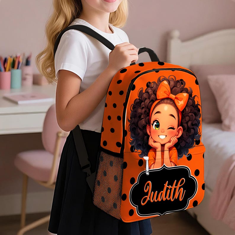 May include: An orange backpack with black polka dots featuring a cartoon illustration of a girl with curly hair and an orange bow. The backpack has a black mesh side pocket and a black rectangular label with the name Judith written in orange script.