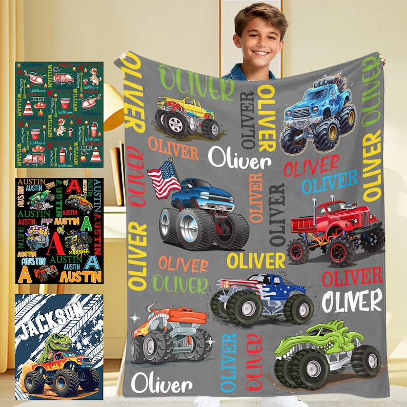 May include: A gray blanket featuring colorful monster truck designs and the name "Oliver" in multiple places. The blanket showcases various monster trucks in blue, red, yellow, orange, and green, with an American flag on one truck.