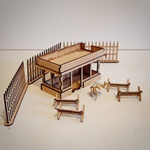 May include: A wooden model of a small building with a roof, windows, and a door. The building is surrounded by a wooden fence and there are several wooden benches in front of it.