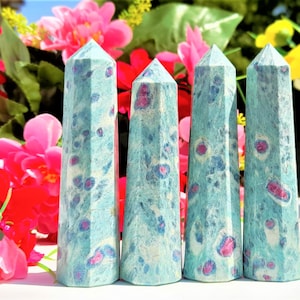 May include: Four blue and white crystal points with pink accents. The points are arranged in a row on a white surface.
