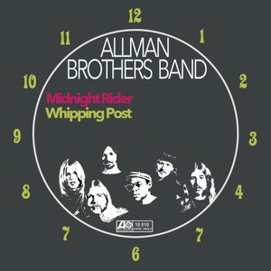 Pode incluir: Uma capa de álbum em preto e branco com um mostrador de relógio com o texto "ALLMAN BROTHERS BAND" e "Midnight Rider Whipping Post". A capa do álbum também apresenta uma foto dos membros da banda.