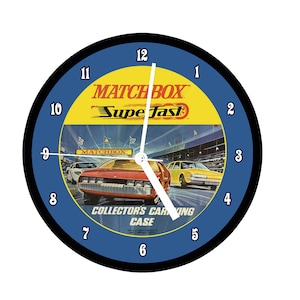 May include: Round wall clock with a blue and black border. The clock face features a vintage Matchbox Superfast design with race cars and the text "Matchbox Superfast" and "Collector's Carrying Case".