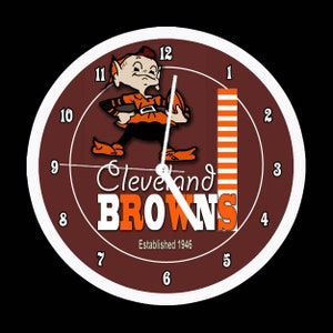 Könnte beinhalten: Eine braune und weiße Uhr mit einem Comic-Elf, der eine braune und orangefarbene Uniform trägt. Das Zifferblatt der Uhr zeigt die Worte "Cleveland Browns" und "Gegründet 1946".
