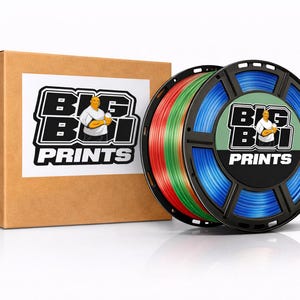 Op de afbeelding: Een bruine kartonnen doos en twee spoelen 3D-printerfilament. De spoelen zijn zwart met blauw, rood en groen filament. De doos en spoelen hebben een wit label met de tekst "BIG BOI PRINTS" en een afbeelding van een man.