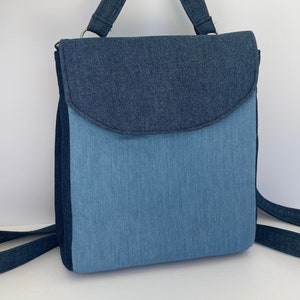 Peut inclure: Un sac à dos en jean bleu avec une fermeture à rabat et des bretelles réglables. Le sac à dos est fait de deux nuances de jean bleu différentes.