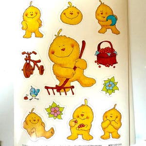 May include: A set of nine yellow fuzzy chick stickers with different expressions and activities. The stickers include a chick holding a rake, a chick holding a basket of red berries, a chick riding a tricycle, a chick holding a ball, and a chick sitting down. The stickers are on a white background with the text "Gimme" at the top and "1985 omega, Inc/Dreamakers. Adapted from the Whimsies" Storybooks #02-12310-0" at the bottom.