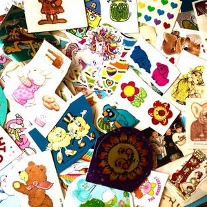 Peut inclure: Une collection d'autocollants vintage avec divers motifs. Les autocollants pr&eacute;sentent une licorne, des fleurs, des animaux et des personnages de dessins anim&eacute;s. Certains autocollants comportent du texte, et la palette de couleurs est vari&eacute;e, avec des teintes vives et pastel.