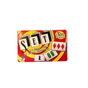 May include: A boxed game of SET, a family game of visual perception. The box is red with a yellow and white spiral design. The word "SET" is in large black letters. Includes game cards with various shapes and colors.