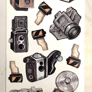May include: A watercolor illustration of nine vintage cameras, including a black and white camera with a flash, a brown camera with a lens, and a black camera with a film roll. The cameras are arranged in a random pattern on a white background.