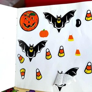 May include: A collection of Halloween-themed stickers featuring jack-o'-lanterns, bats, and candy corn. The stickers are in various sizes and are primarily orange, black, and yellow. The stickers are on a white background.