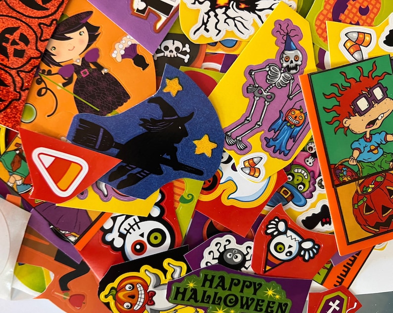 May include: A colorful assortment of Halloween-themed scrapbook paper featuring various characters, including a witch, a skeleton, and a cartoon character. The paper is decorated with pumpkins, candy corn, and other Halloween symbols. The text "Happy Halloween" is visible on one of the papers.