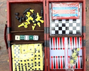May include: A red, hinged travel game set with multiple games. The set includes chess pieces, dice, dominoes, and a backgammon board. The chess board is black and white. The dominoes are yellow with black dots. The backgammon board has red and black triangles.