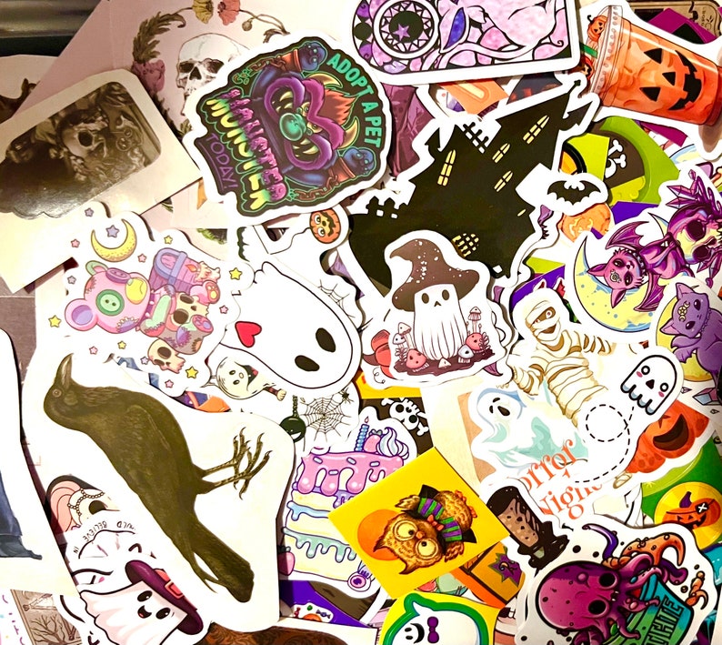 May include: A collection of Halloween themed stickers featuring various designs, including a black cat, a ghost, a skeleton, a haunted house, and a crow. The stickers are colorful and feature a variety of textures and patterns.