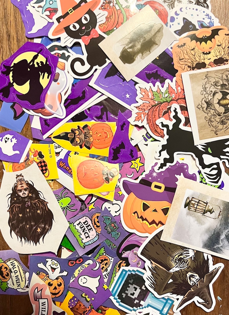 May include: A collection of Halloween themed stickers featuring various designs including pumpkins, ghosts, bats, witches, and a black cat. The stickers are on a wooden surface.