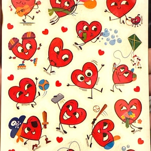 May include: Sheet of "Stinky Stickers" featuring red cartoon hearts with various accessories and activities. The stickers include hearts playing guitar, holding balloons, and playing baseball. The text "Cinnamon Scratch 'n Sniff" is at the top.
