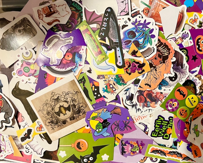 May include: A collection of colorful Halloween themed stickers featuring various designs, including bats, ghosts, pumpkins, and witches. The stickers are arranged in a random pattern on a white surface.