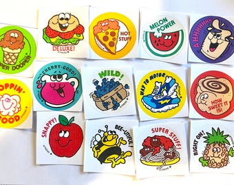 May include: A set of 12 colorful round stickers featuring various cartoon characters and food items. The stickers have a white background with a black outline and feature phrases like "Cherry-Good!" and "How Sweet It Is!"
