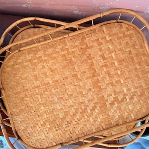 May include: A rectangular serving tray crafted from light brown woven rattan with a sturdy bamboo frame. The base features a tight, intricate basket-weave pattern, while the raised sides are constructed from curved bamboo rods.