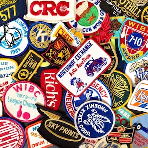 May include: A collection of colorful embroidered patches with various designs and text, including "SSG 577", "CRC", "WIBC 7-10 AWARD", "NORTHWAY EXCHANGE Auto Auction", "Rich's", "SKY PRINTS", and "Rampart 1984".