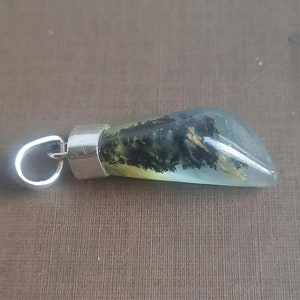 May include: A silver pendant with a green, black, and white agate stone. The stone is shaped like a teardrop and has a silver bail.