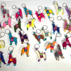 May include: A collection of colorful llama keychains with intricate woven patterns. Each keychain features a small, plush llama with a silver key ring.