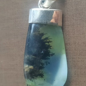 May include: A silver pendant with a green, blue, and black agate stone. The stone has a dendritic pattern. The pendant is marked with "950" on the bail.