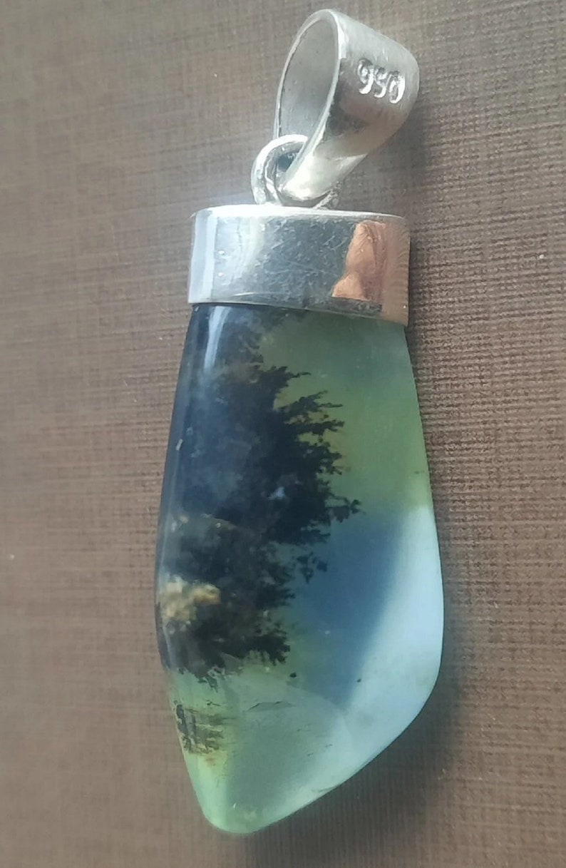 May include: A silver pendant with a green, blue, and black agate stone. The stone has a dendritic pattern. The pendant is marked with "950" on the bail.
