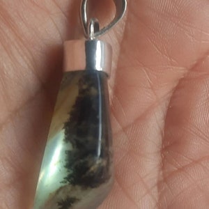 May include: A silver pendant with a green and black agate stone. The stone is a teardrop shape and has a silver bail.