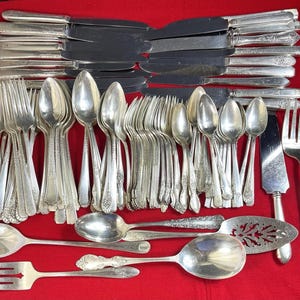 Lote de 100 piezas de cubiertos vintage plateados: tenedores, cucharas y cuchillos de marcas variadas.