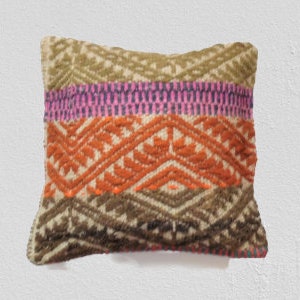 Peut inclure: Un coussin carr&eacute; avec un motif tiss&eacute; color&eacute;. Le coussin a un fond blanc avec des rayures brunes, orange, roses et vertes et des motifs g&eacute;om&eacute;triques.