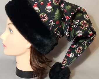 May include: Black and green Christmas hat with a skull and crossbones pattern. The hat has a black faux fur trim and a black pom-pom.
