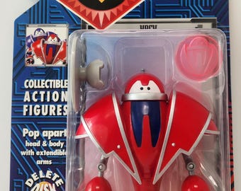 May include: Collectible action figure of a red robot with blue and silver accents, packaged in a clear plastic case. The packaging features the "ReBoot" logo and text that reads "Pop apart head & body with extendible arms."