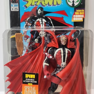 May include: A Spawn action figure in a clear plastic package. The figure is red, black, and white, with a large red cape. The packaging includes the text "SPAWN" and "SPECIAL EDITION COMIC BOOK". The figure is from Todd McFarlane.