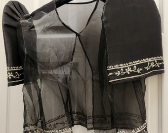 May include: Black sheer top with embroidered floral details and puff sleeves. The top has a V-neckline and a button closure.