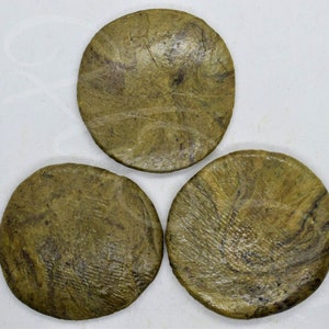 May include: Three round, green and brown coasters with a marbled pattern. The coasters are made of a natural material and have a rustic look.