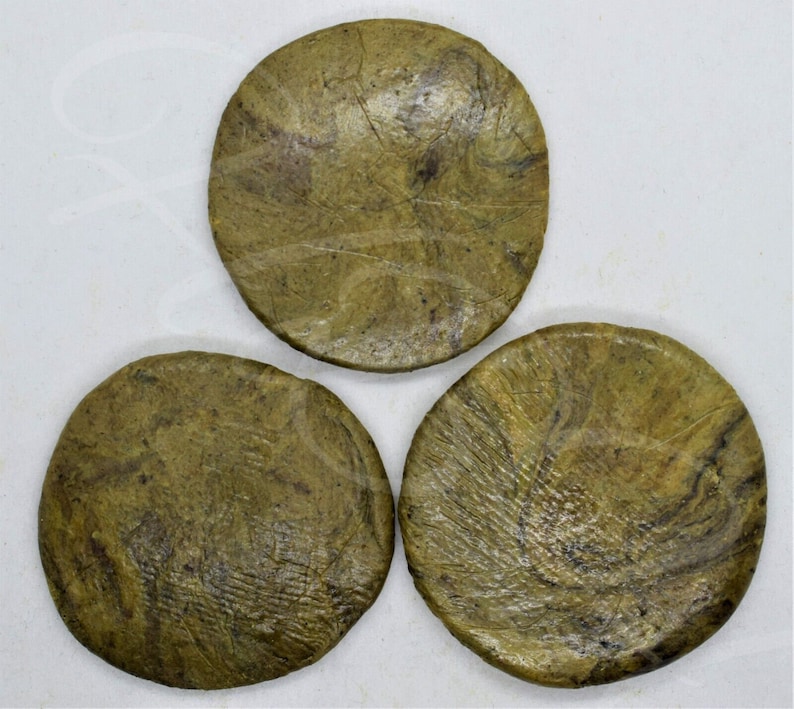 May include: Three round, green and brown coasters with a marbled pattern. The coasters are made of a natural material and have a rustic look.